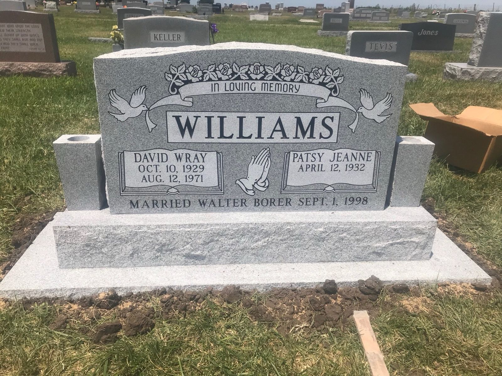 Wide grey granite companion monument with carved doves and a rose garland, standing installed in a Missouri cemetery