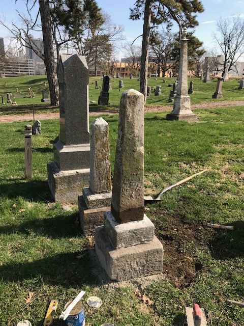Three tall nineteenth century granite obelisks reset upright and plumb, with the Kansas City skyline in the distance