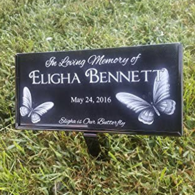 Black temporary grave marker on a steel stake, etched with a name and butterflies